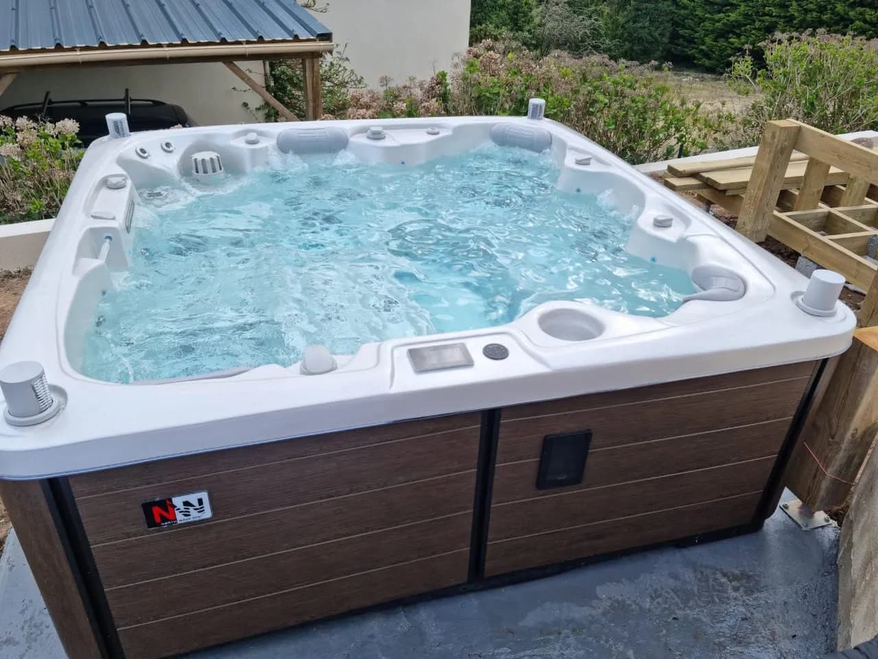 Installation d'un spa Hølen, dans un jardin, tablier brun façon bois