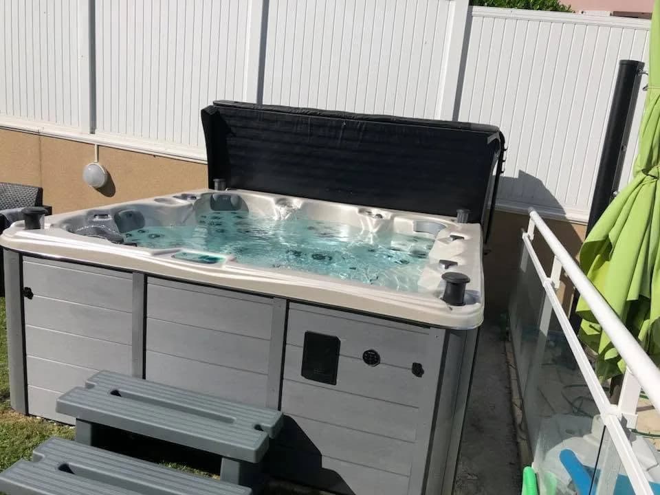 Installation d'un autre spa Cambridge Duel Full option dans le Haut-Rhin, au bord du gazon devant une palissade blanche