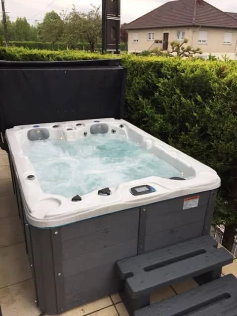 Installation d'un autre spa Montana en Meurthe-et-Moselle, sur un dallage devant une haie, marchepied