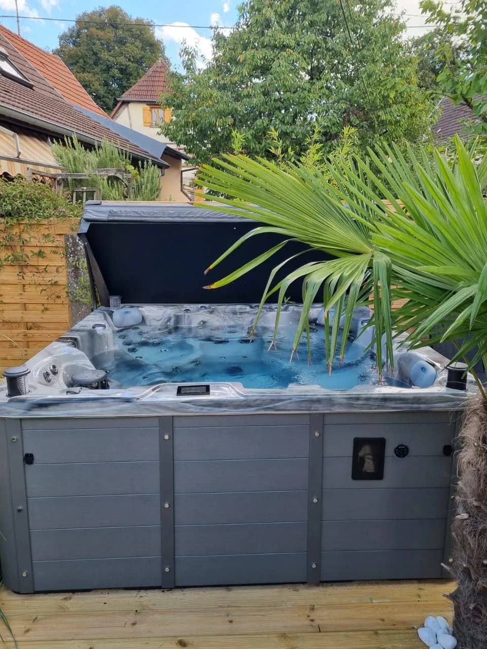 Installation d'un autre spa Montréal Full option, sur une terrasse en bois entre palmiers