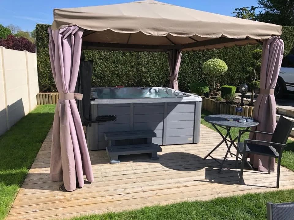 Installation d'un autre spa Vancouver dans les Ardennes, sous une tonnelle à rideaux sur une terrasse en bois