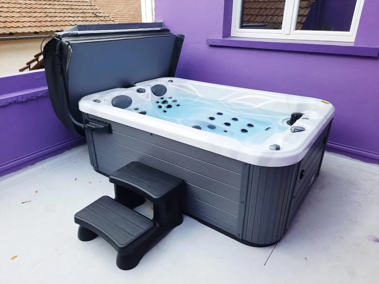Installation d'un spa Apollon à Neuf-Brisach, sur une terrasse aux murs violets, marchepied