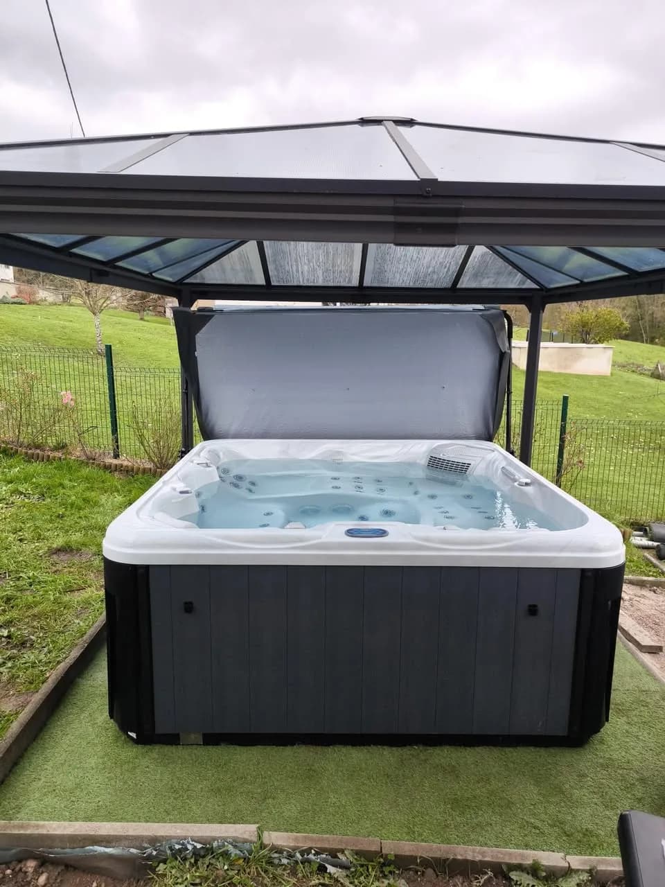 Installation d'un spa Athena à La Vancelle, sous une tonnelle en bordure de pré