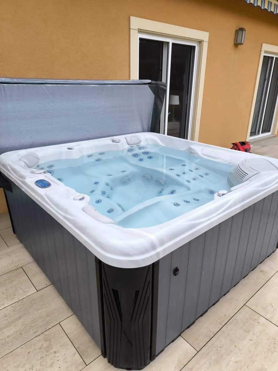 Installation d'un spa Athena, sur une terrasse carrelée devant la maison