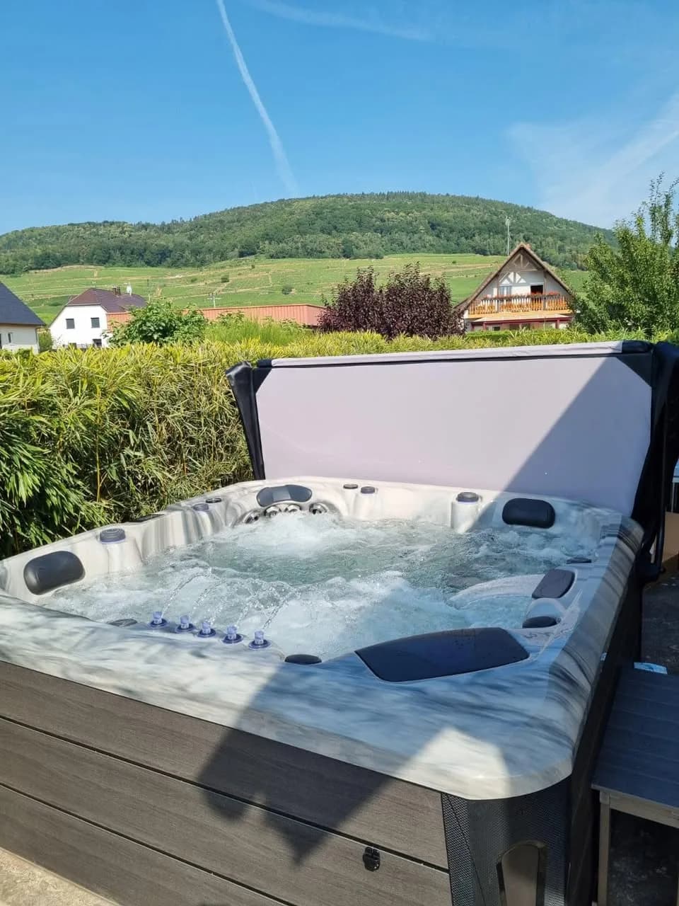 Installation d'un spa Barcelona à Bergholtz, devant une haie, vue sur les collines