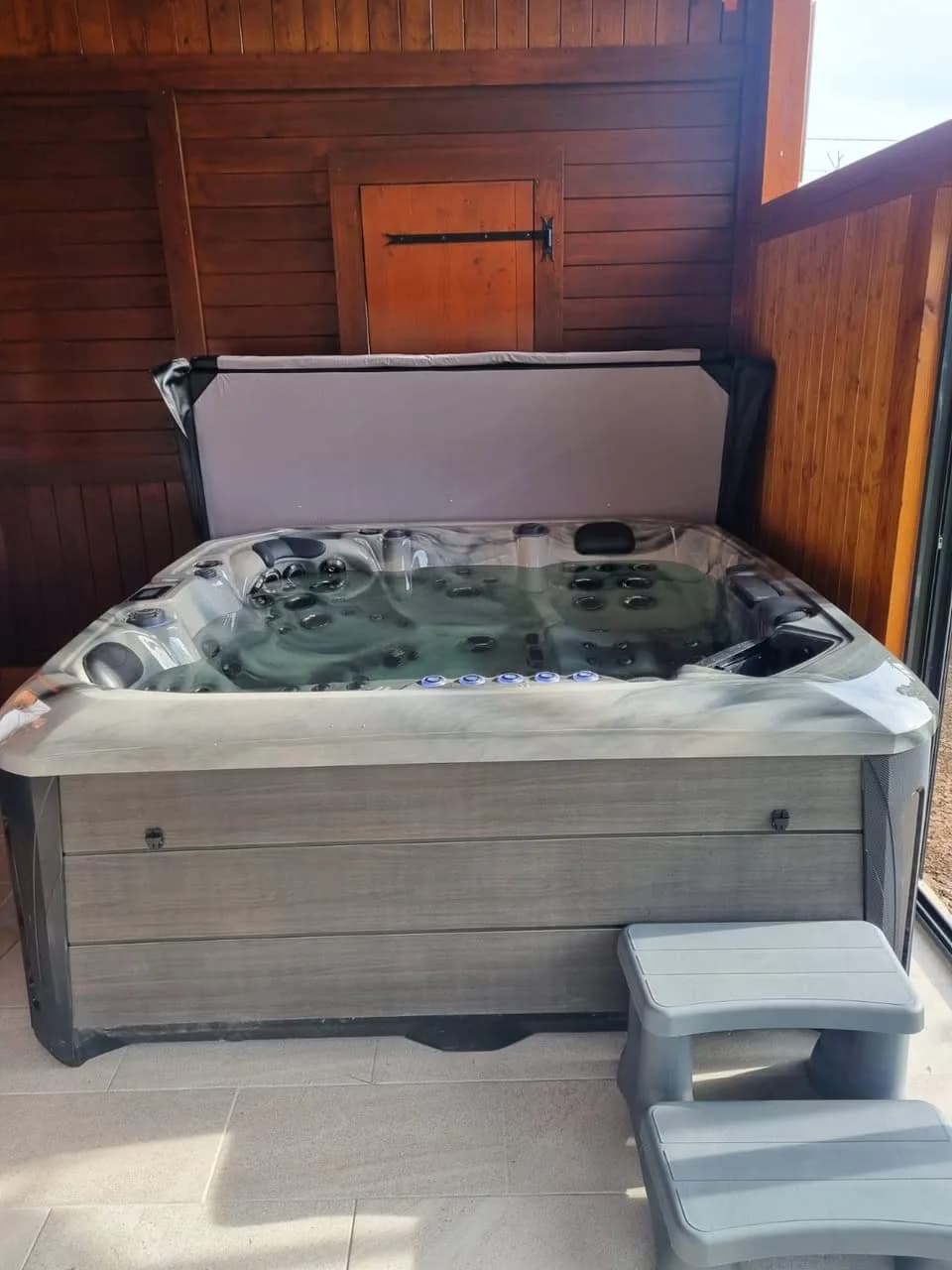 Installation d'un spa Barcelona à Le Val-d'Ajol, sous un abri en bois, marchepied