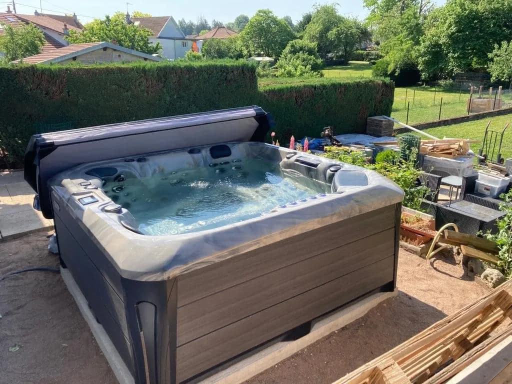 Installation d'un spa Barcelona à Lure, sur une dalle face au jardin, lève-couverture
