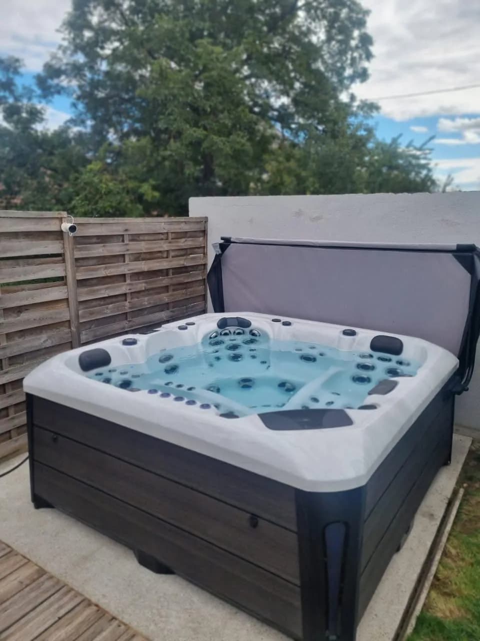Installation d'un spa Barcelona à Pfaffenheim, sur une terrasse en bois devant une palissade