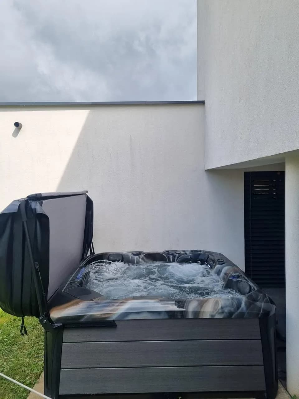 Installation d'un spa Barcelona à Zillisheim, contre la façade, lève-couverture