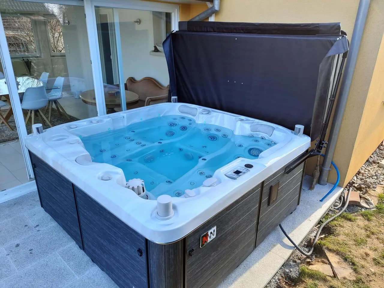 Installation d'un spa Bjørgan Full option à Feldbach, sur une terrasse dallée contre la maison