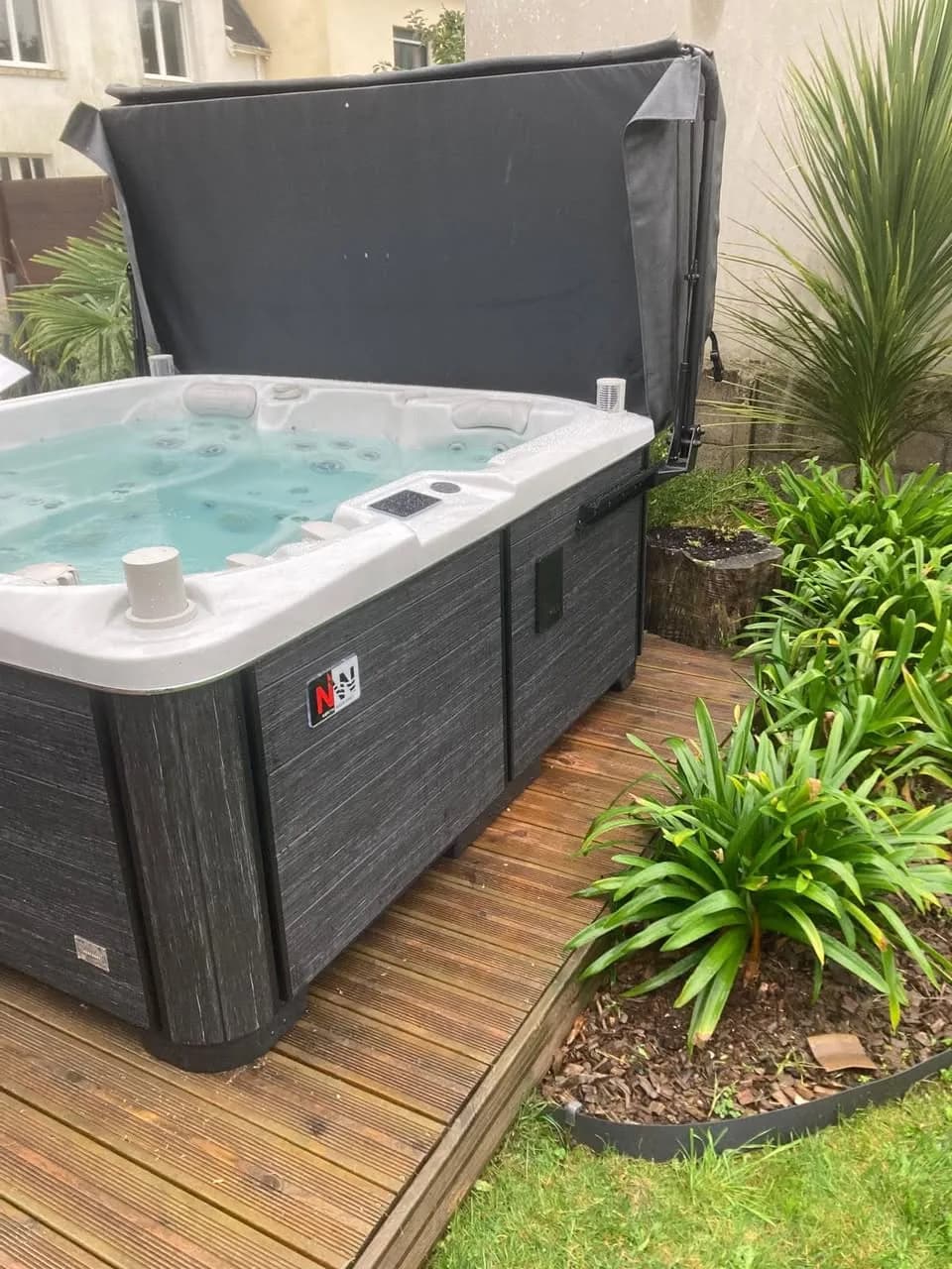 Installation d'un spa Bjørgan Full option à Île-Tudy, sur une terrasse en bois bordée de fleurs