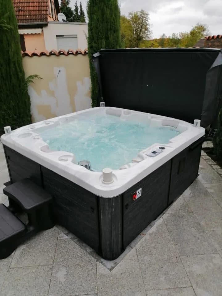 Installation d'un spa Bjørgan Full option à Seltz, sur une terrasse pavée, lève-couverture