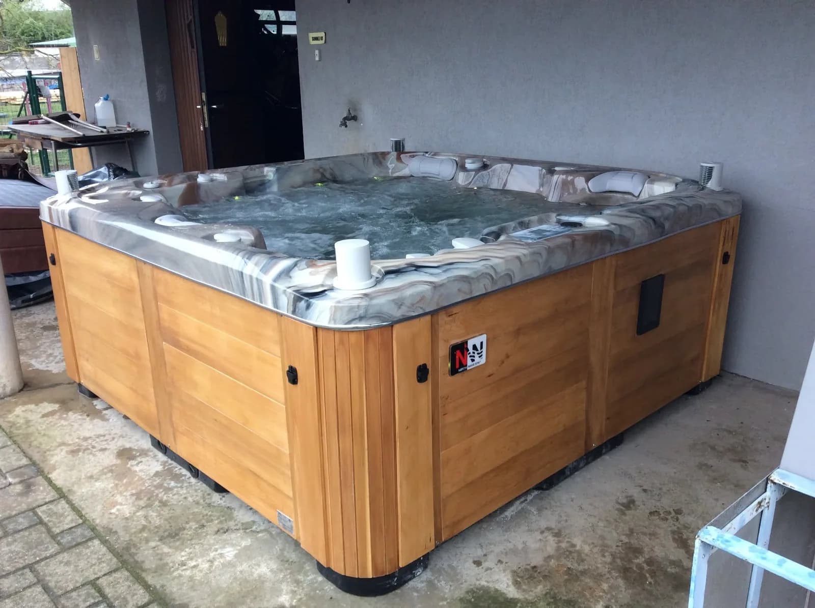 Installation d'un spa Bjørgan, sur une dalle sous un auvent, tablier en cèdre