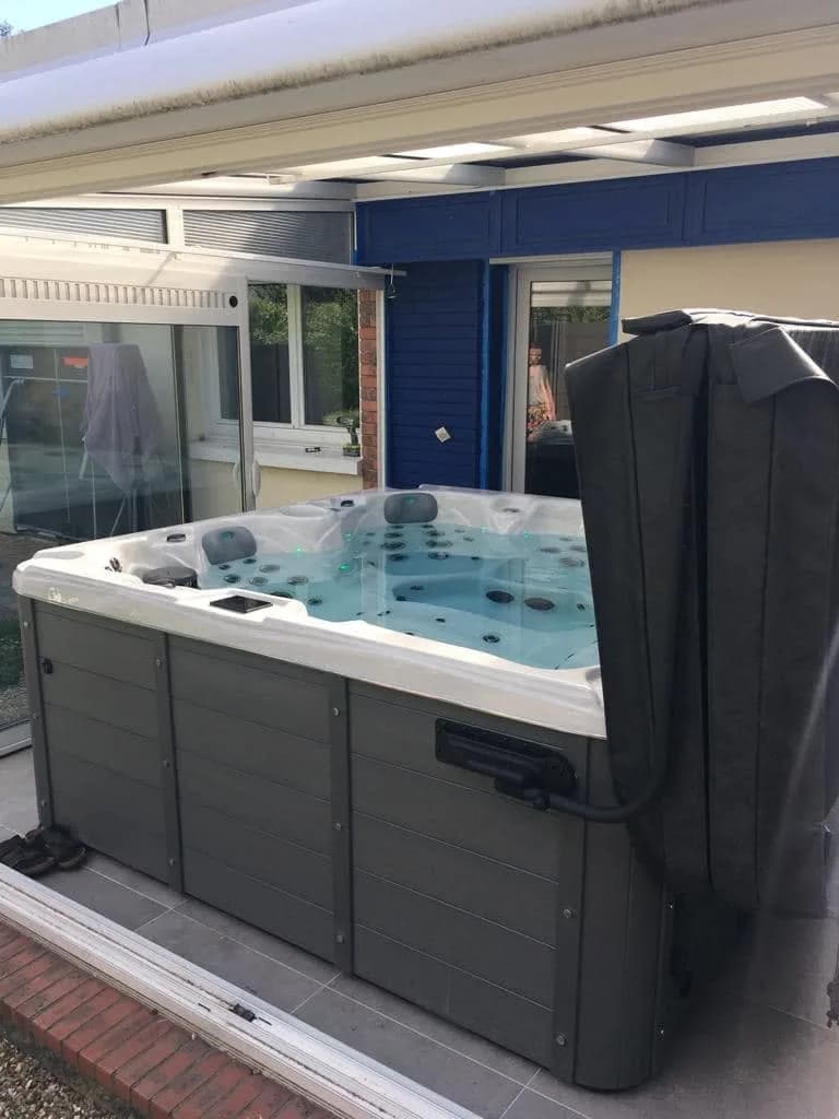 Installation d'un spa Cambridge à Bonsecours, sous une véranda, couverture relevée