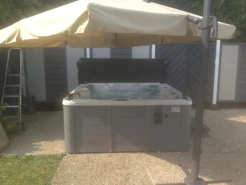 Installation d'un spa Cambridge Duel Full option en Moselle, sous un grand parasol, marchepied