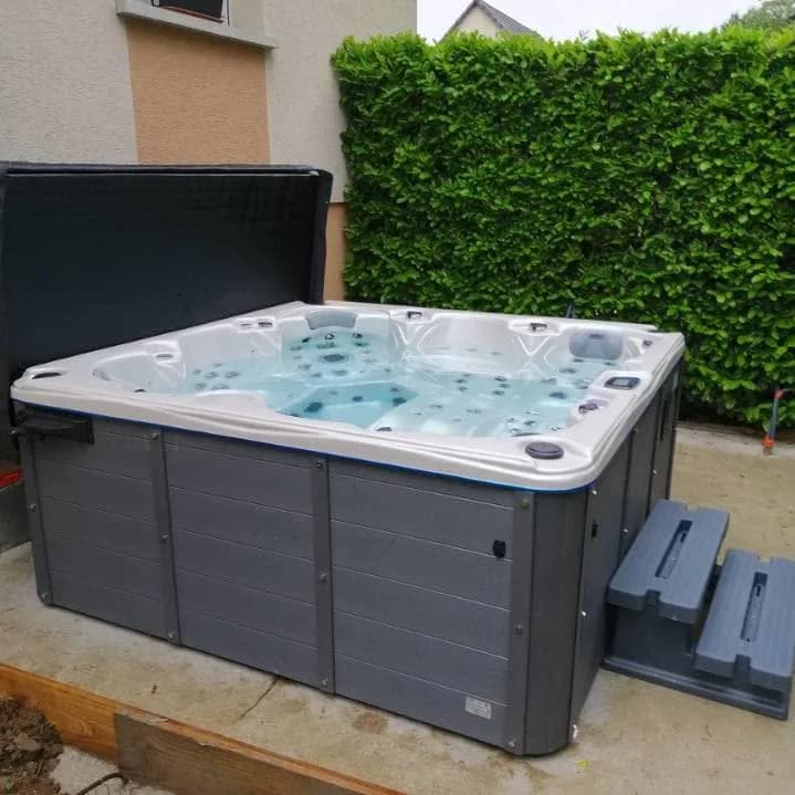 Installation d'un spa Cambridge Duel Full option à Lutterbach, sur une dalle devant une haie