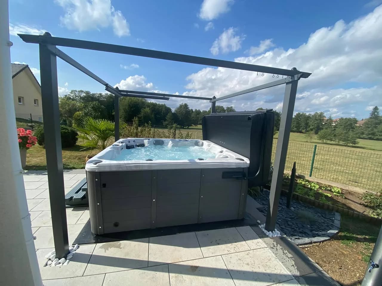 Installation d'un spa Cambridge Duel Full option à Lyoffans, sous une pergola métallique, face aux prés
