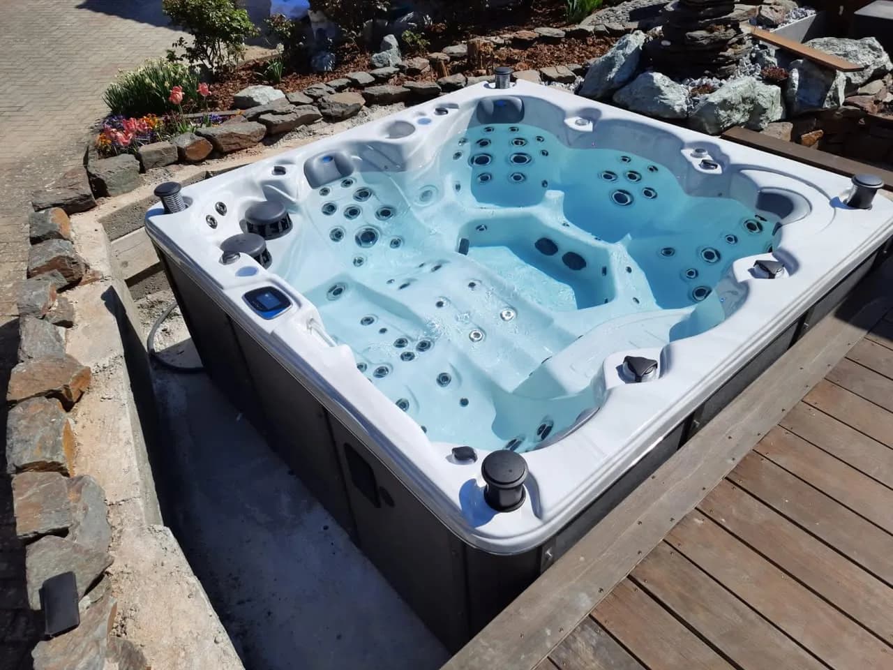 Installation d'un spa Cambridge Duel Full option à Niedernai, contre une terrasse en bois et une rocaille