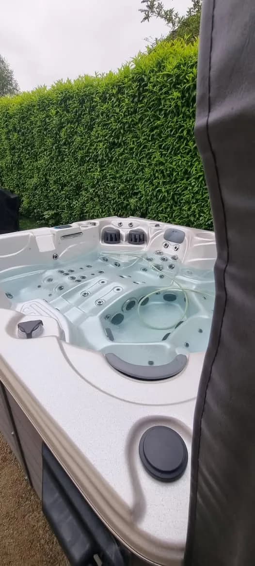 Installation d'un spa Cambridge Duel Full option à Sausheim, devant une haie, couverture relevée