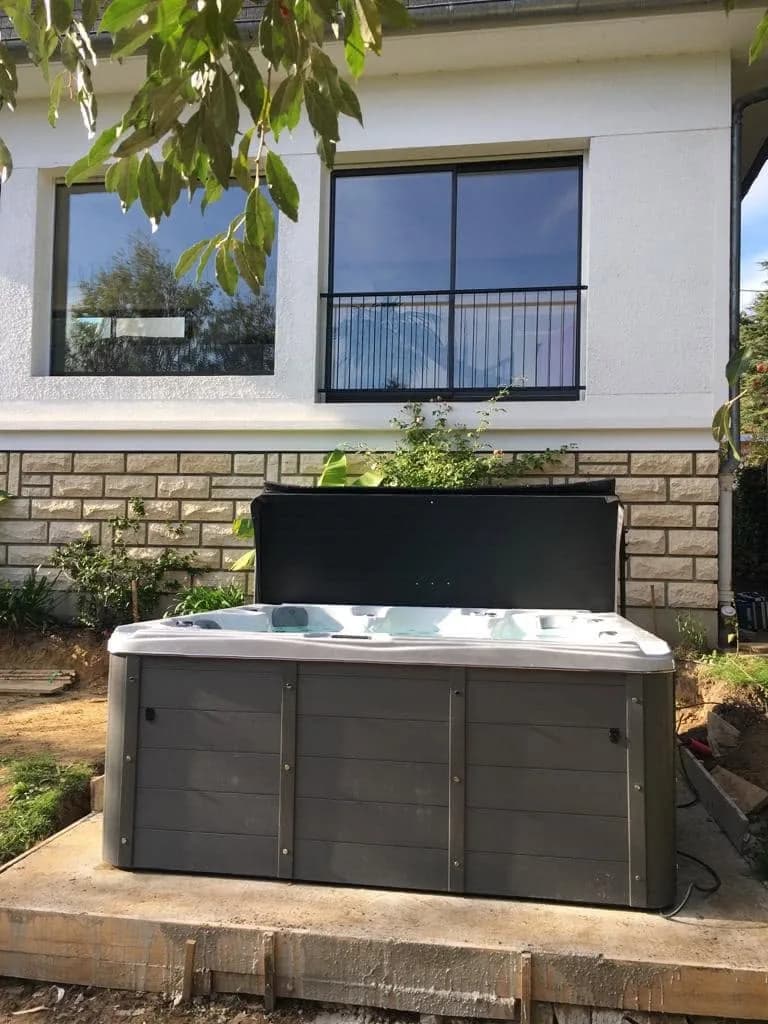 Installation d'un spa Cambridge Duel à La Celle-Saint-Cloud, devant la maison, au pied d'un muret en pierre
