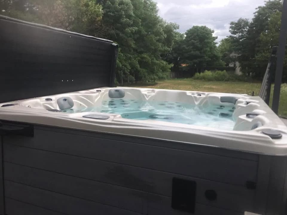 Installation d'un spa Cambridge Duel à Rixheim, dans un jardin, couverture relevée