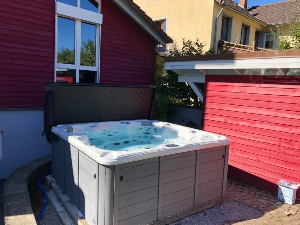 Installation d'un spa Cambridge Duel à Staufen im Breisgau, contre un bardage en bois rouge