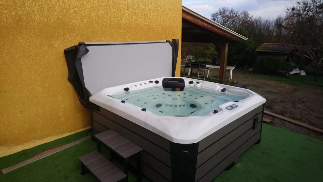 Installation d'un spa Caraïbes Full option en Haute-Garonne, sur un gazon synthétique contre un mur
