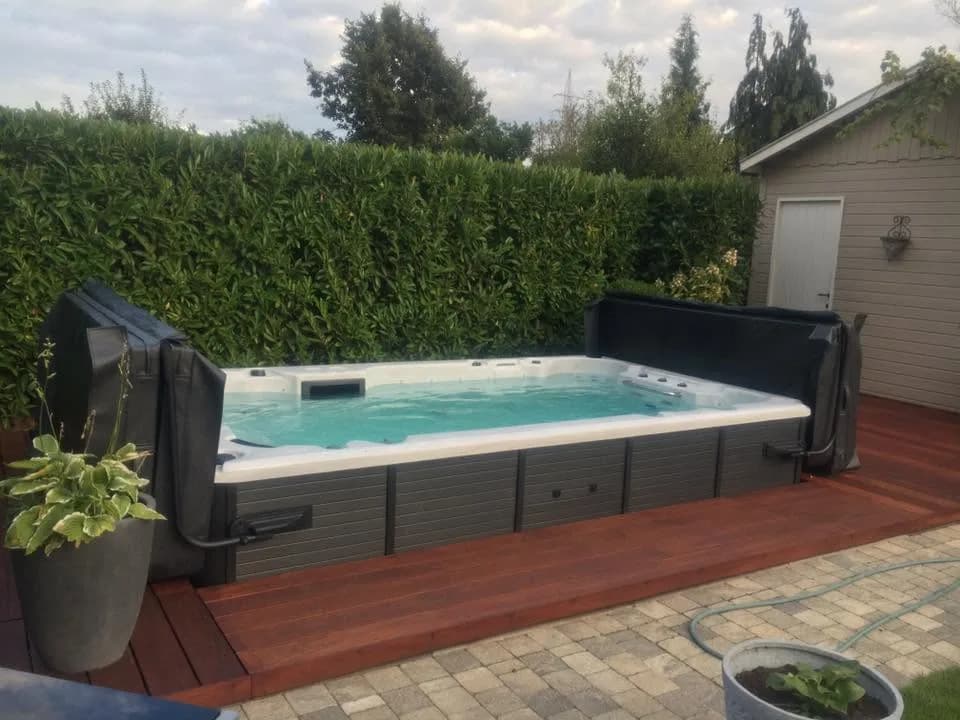 Installation d'un spa de nage en Côte-d'Or, sur une terrasse en bois devant une haie