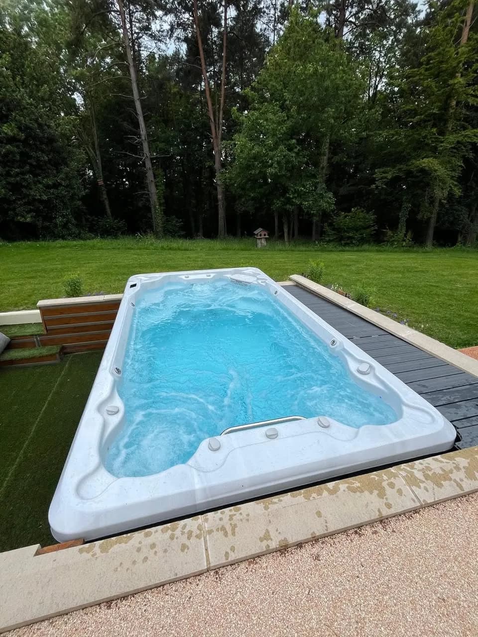 Installation d'un spa de nage Førde 410 en Seine-et-Marne, dans une ancienne piscine, entouré de gazon synthétique