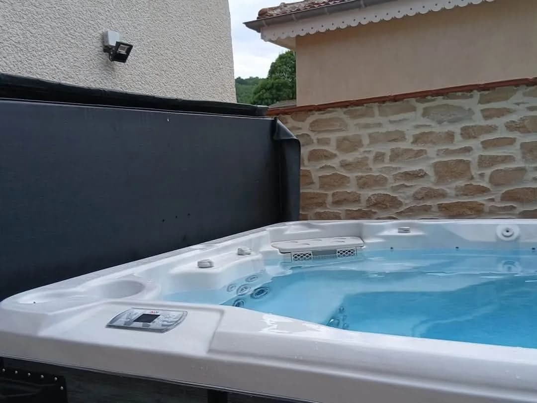 Installation d'un spa de nage Førde 410 à Lens-Lestang, contre un mur en pierre, sur un sol carrelé