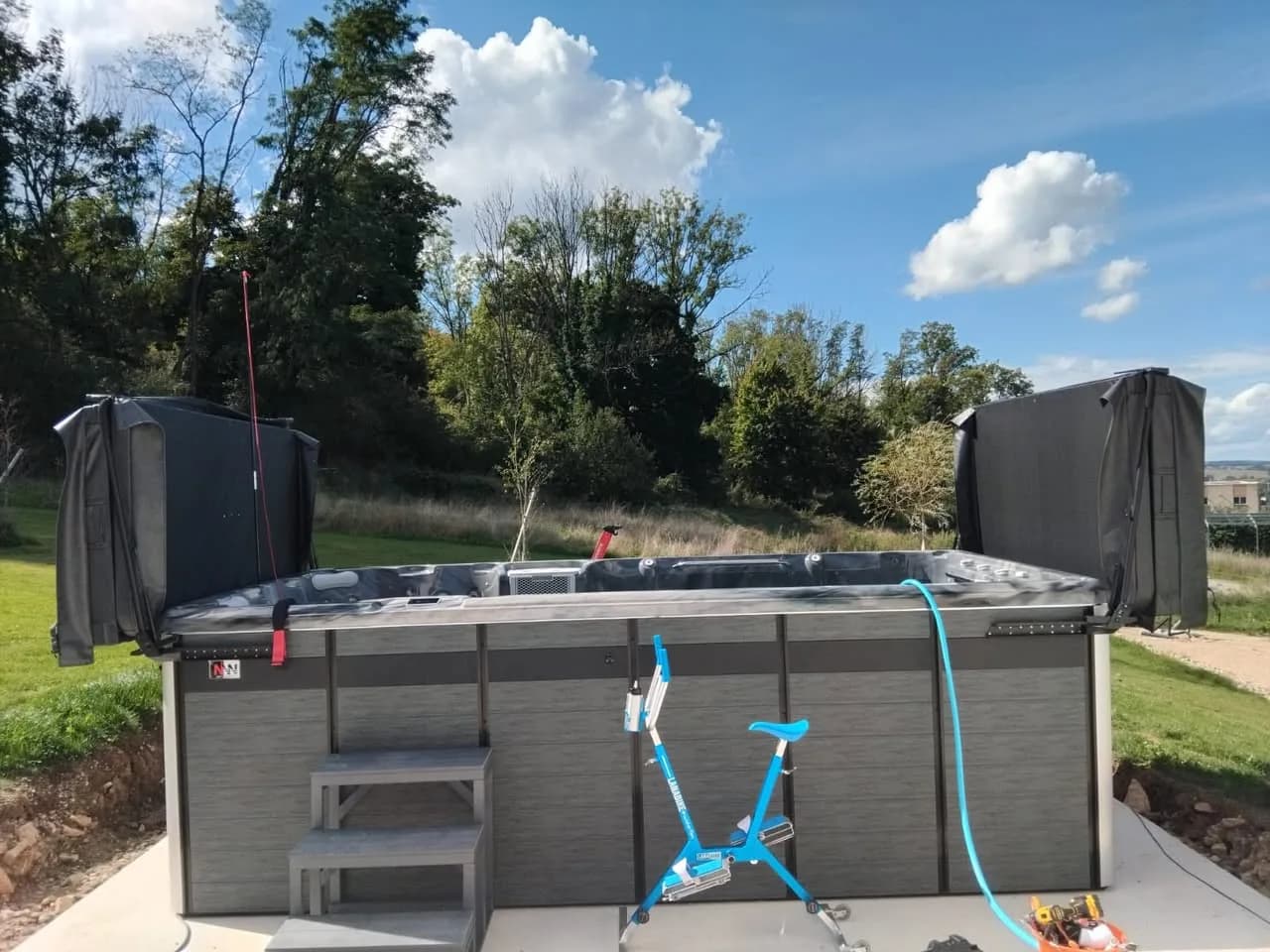 Installation d'un spa de nage Øxford 480, sur une pelouse, avec un aquabike