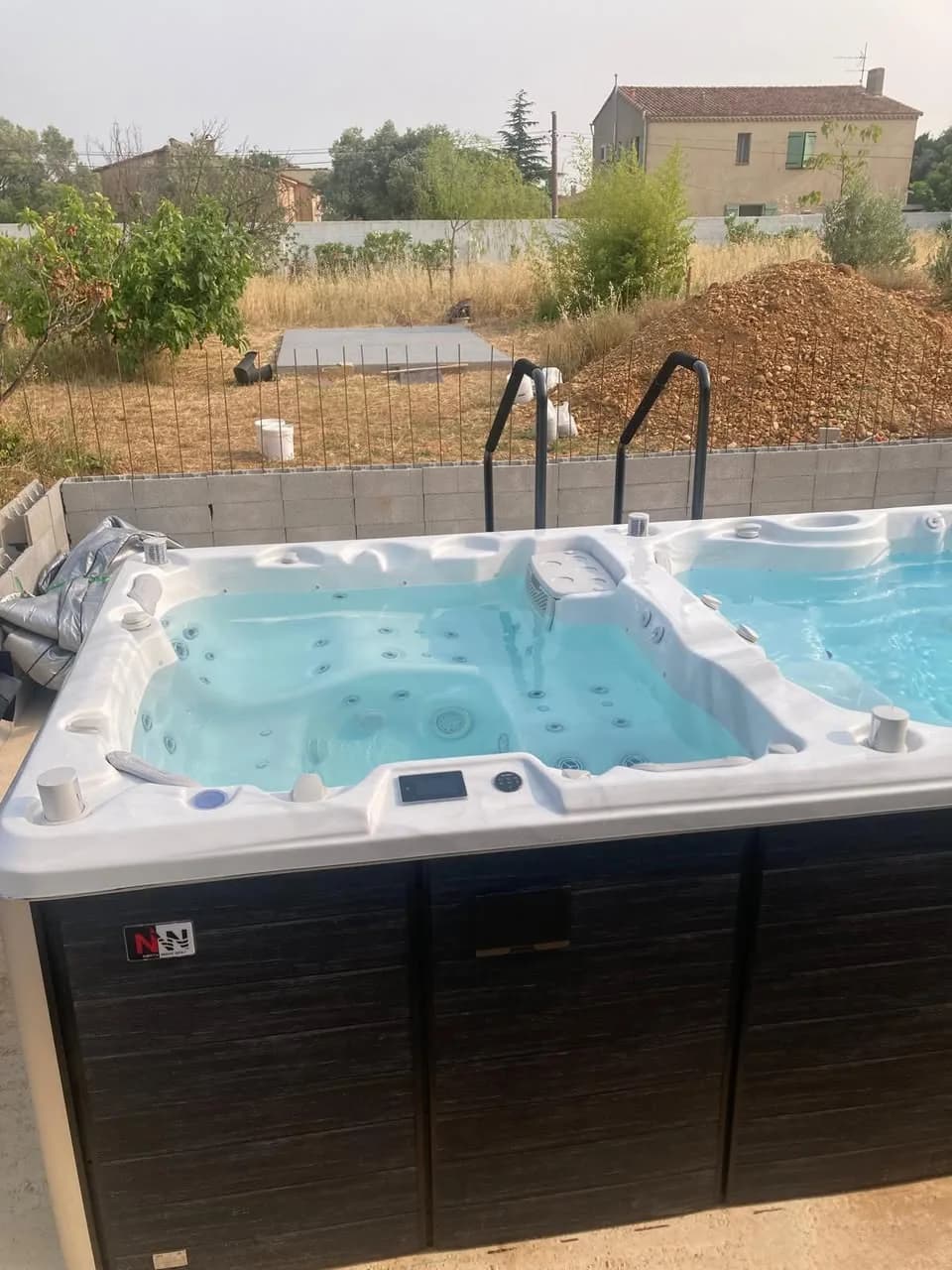 Installation d'un spa de nage Risør 600 Full option à Arles, sur un terrain en cours d'aménagement, rampes d'accès