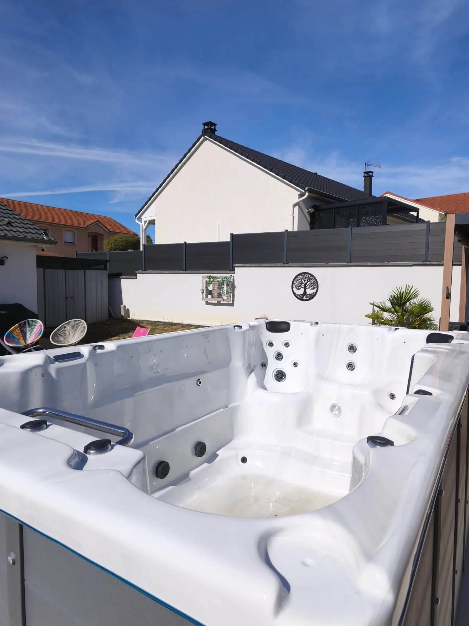 Installation d'un spa de nage Waterloo 390 à Coincy, sur une terrasse carrelée devant la maison