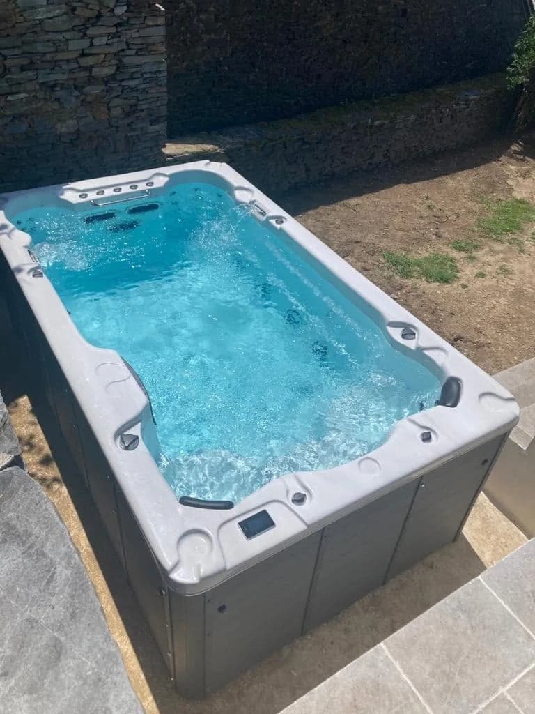 Installation d'un spa de nage Waterloo 390 à Donzenac, sur une terrasse dallée en bordure de pelouse