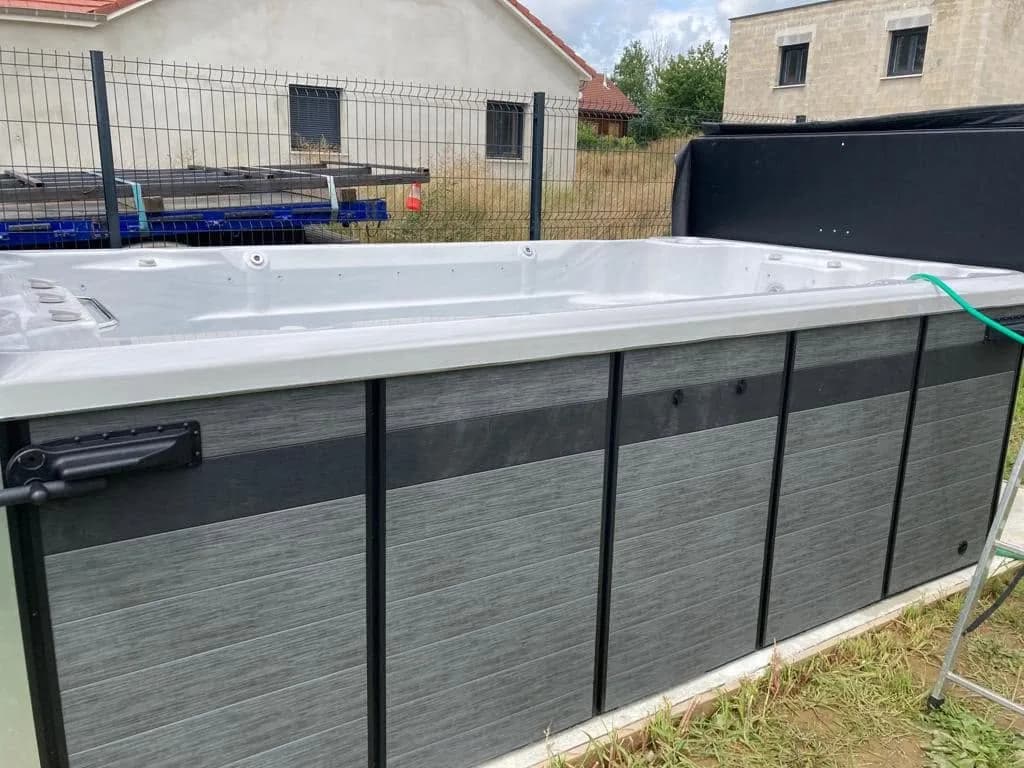 Installation d'un spa de nage Waterloo 410 à Vézelois, en bordure de pré le long d'une clôture