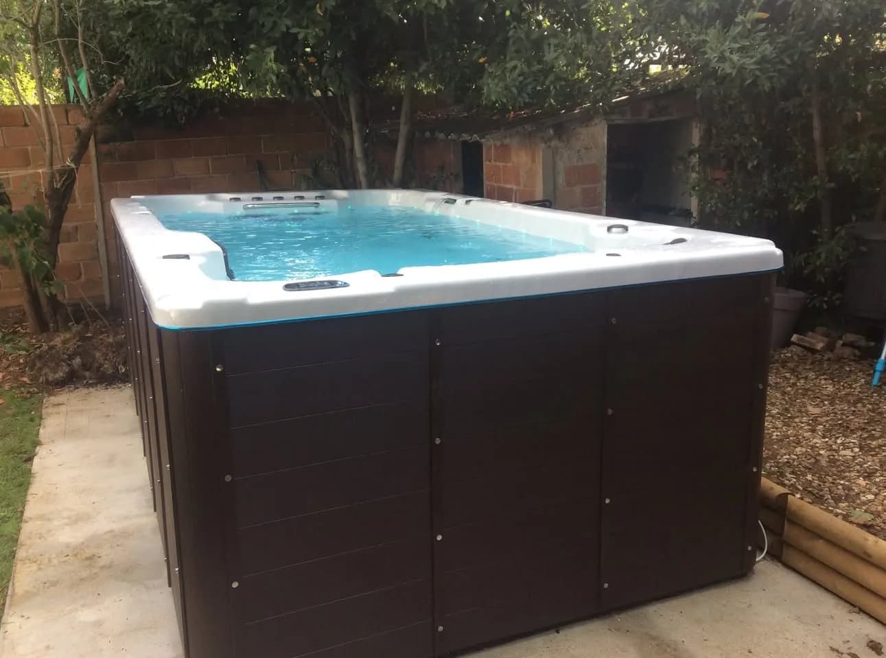 Installation d'un spa de nage Waterloo 421 à Bourg-la-Reine, sur une dalle au fond du jardin