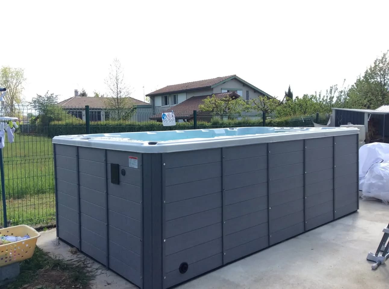 Installation d'un spa de nage Waterloo 421 en Isère, sur une dalle dans le jardin