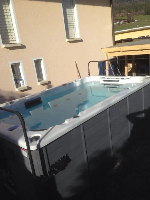 Installation d'un spa de nage Waterloo 421 Full option en Suisse, contre la maison, vue sur les collines