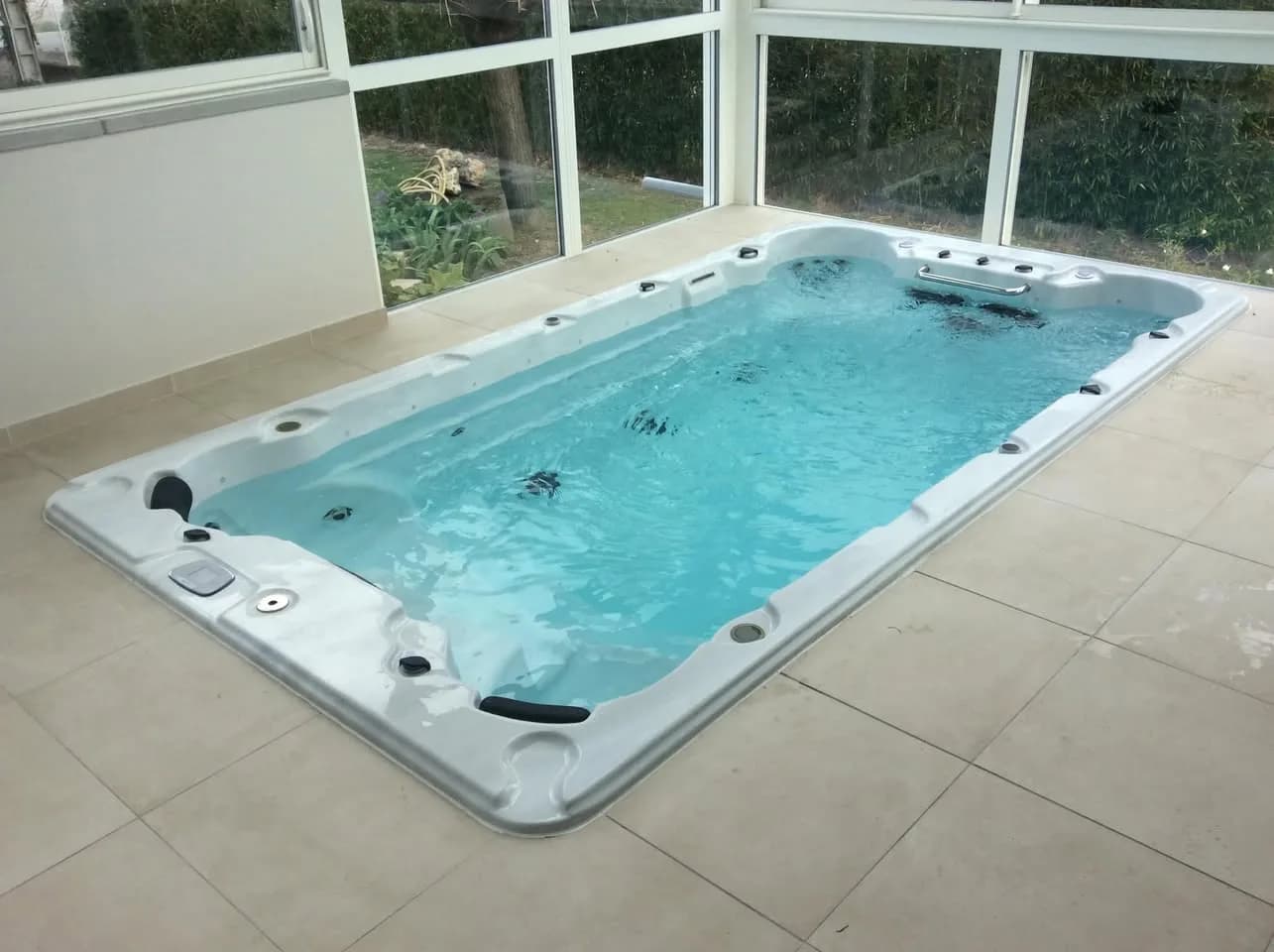 Installation d'un spa de nage Waterloo 421 à Merville, encastré sous une véranda vitrée