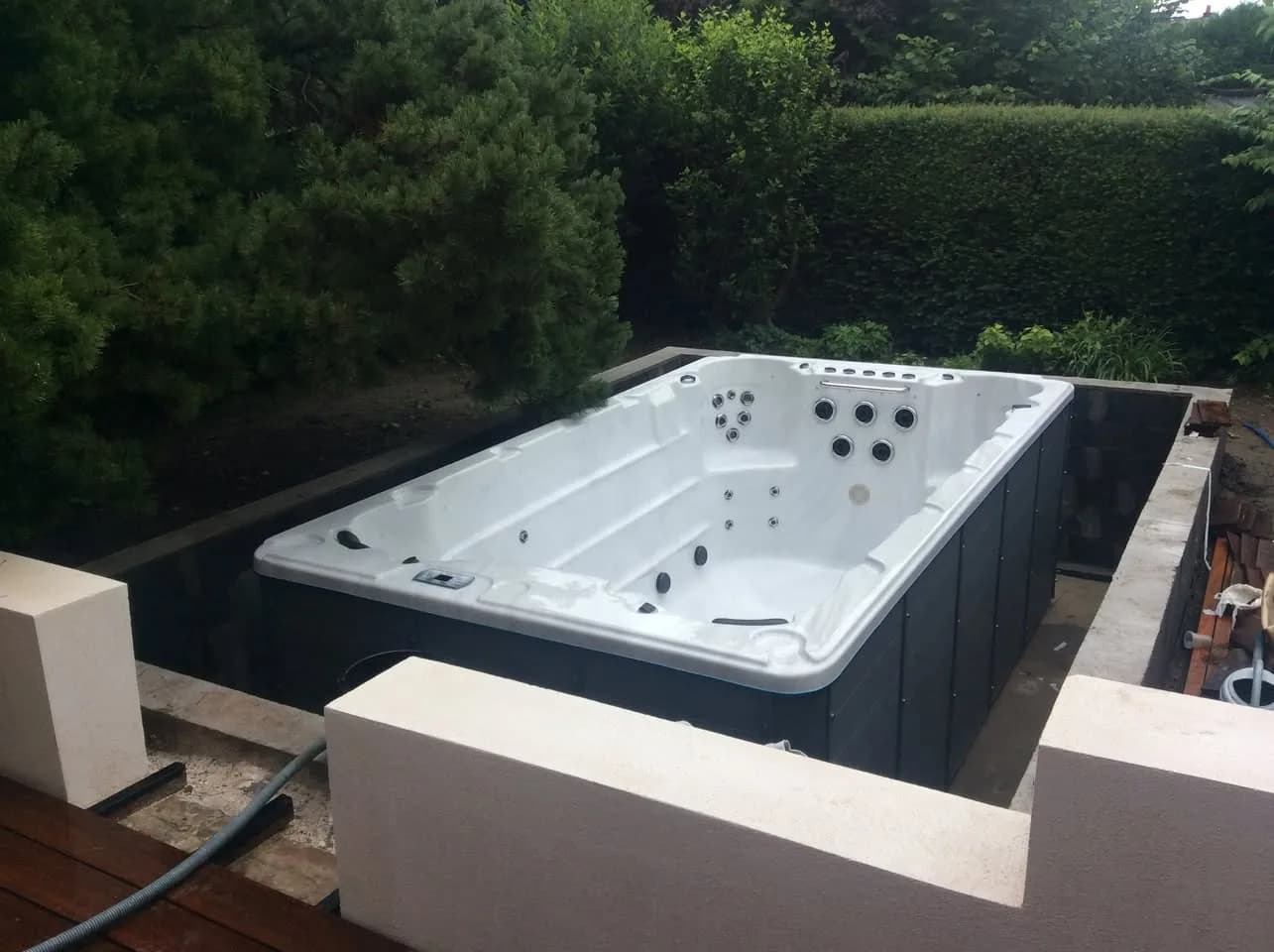 Installation d'un spa de nage Waterloo 421 à Valenciennes, posé dans un muret au fond d'un jardin