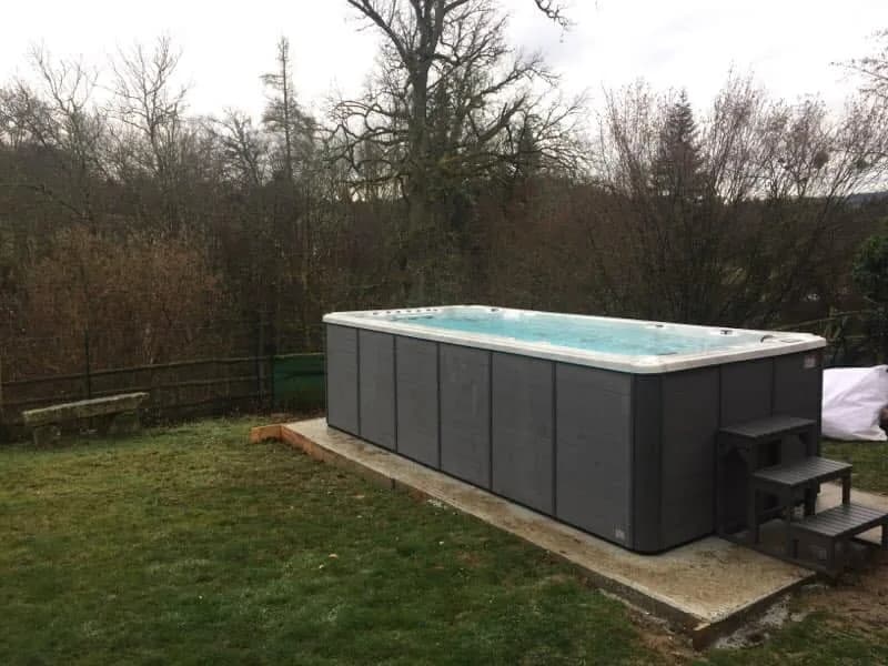 Installation d'un spa de nage Waterloo 501 à Clermont-Ferrand, sur une dalle dans un grand jardin