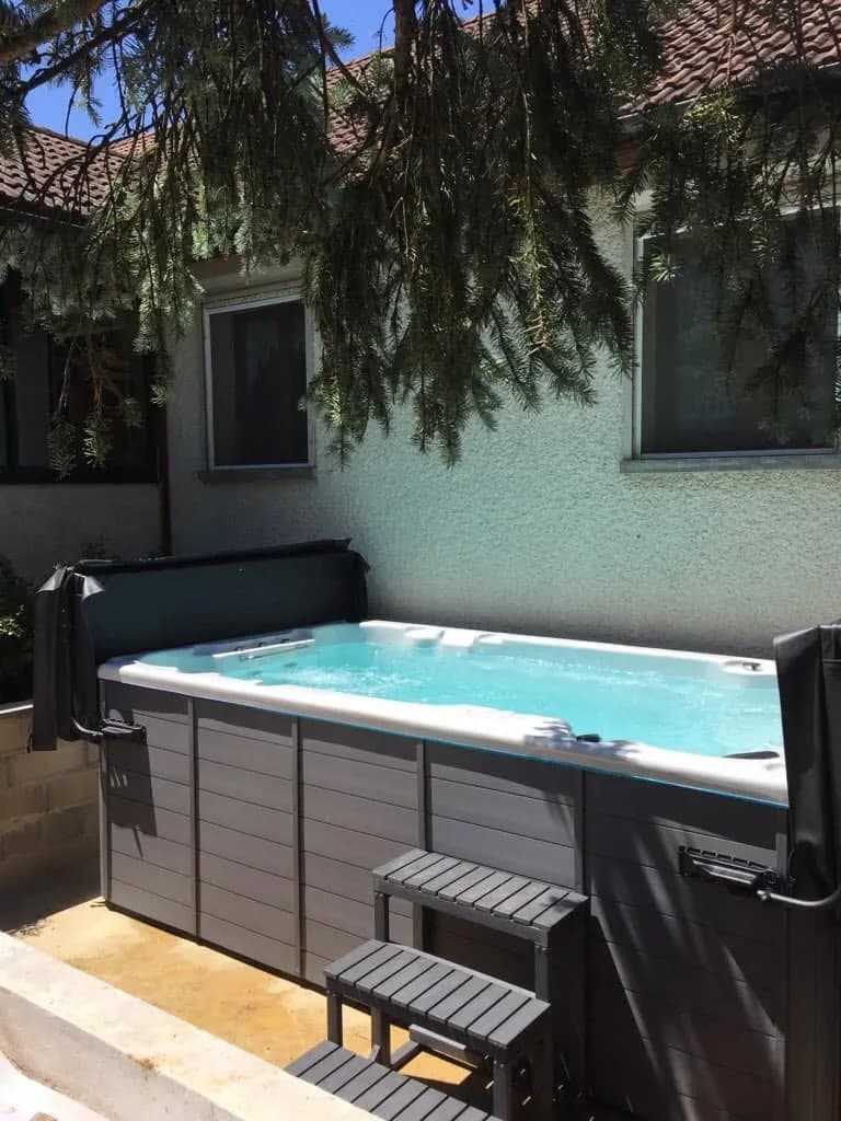 Installation d'un spa de nage Waterloo 501 en Côte-d'Or, sur un sol gravillonné contre la maison