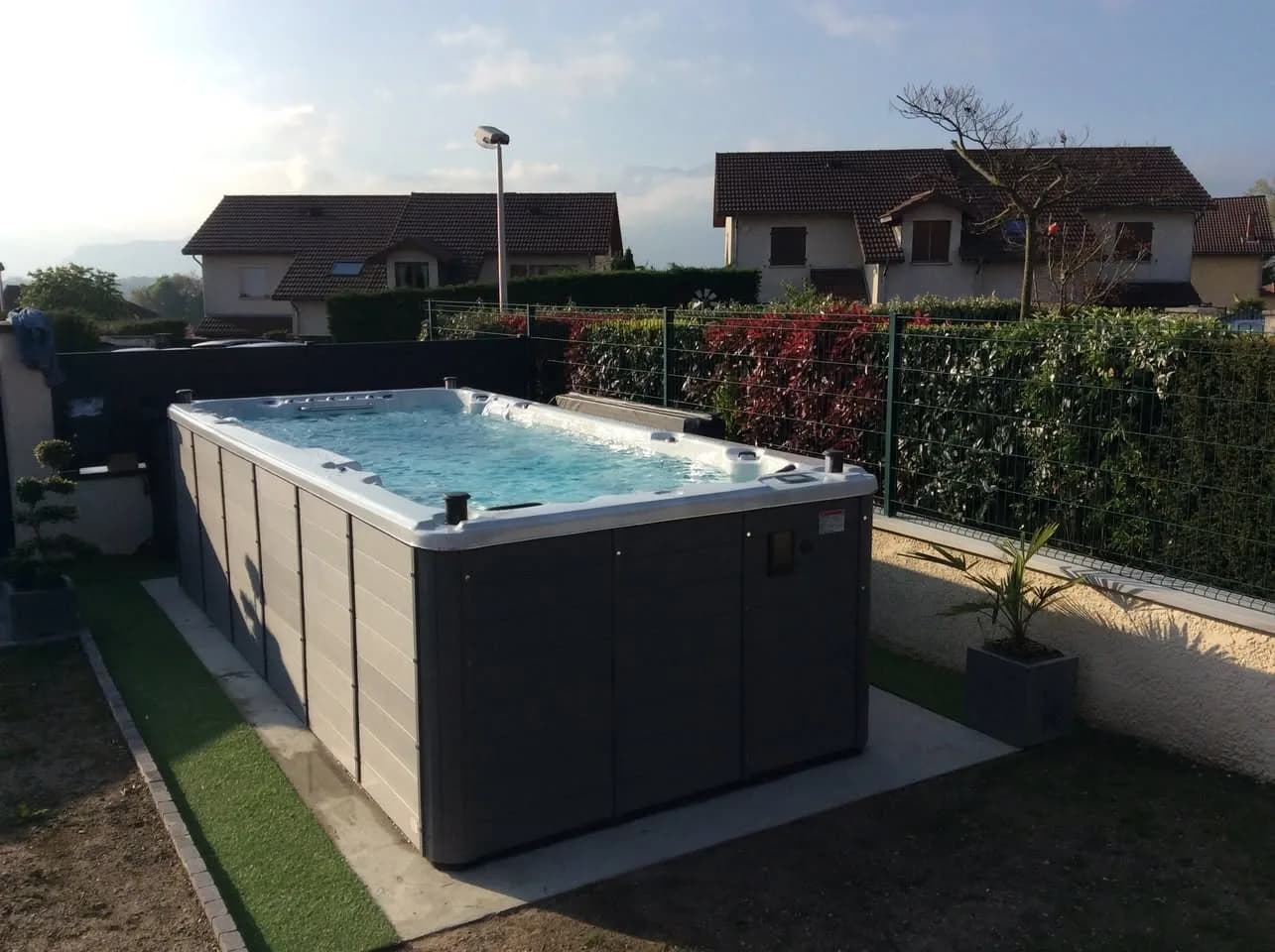 Installation d'un spa de nage Waterloo 501 Full option en Isère, sur une dalle au bord du jardin