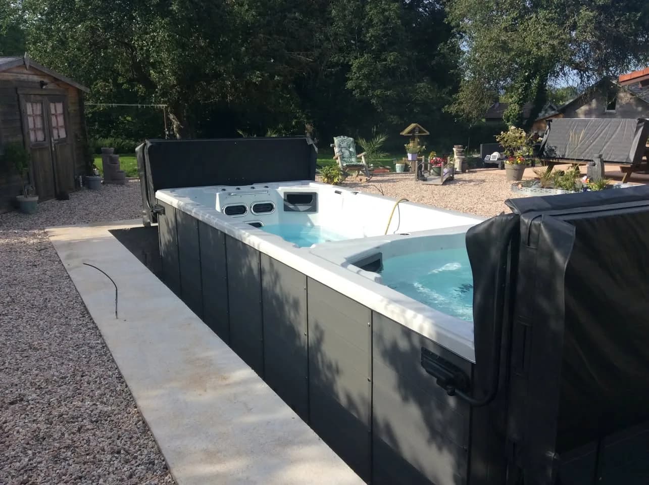 Installation d'un spa de nage Waterloo 594 Full option à Saint-Michel-sur-Meurthe, semi-encastré, bordé de béton et de gravier