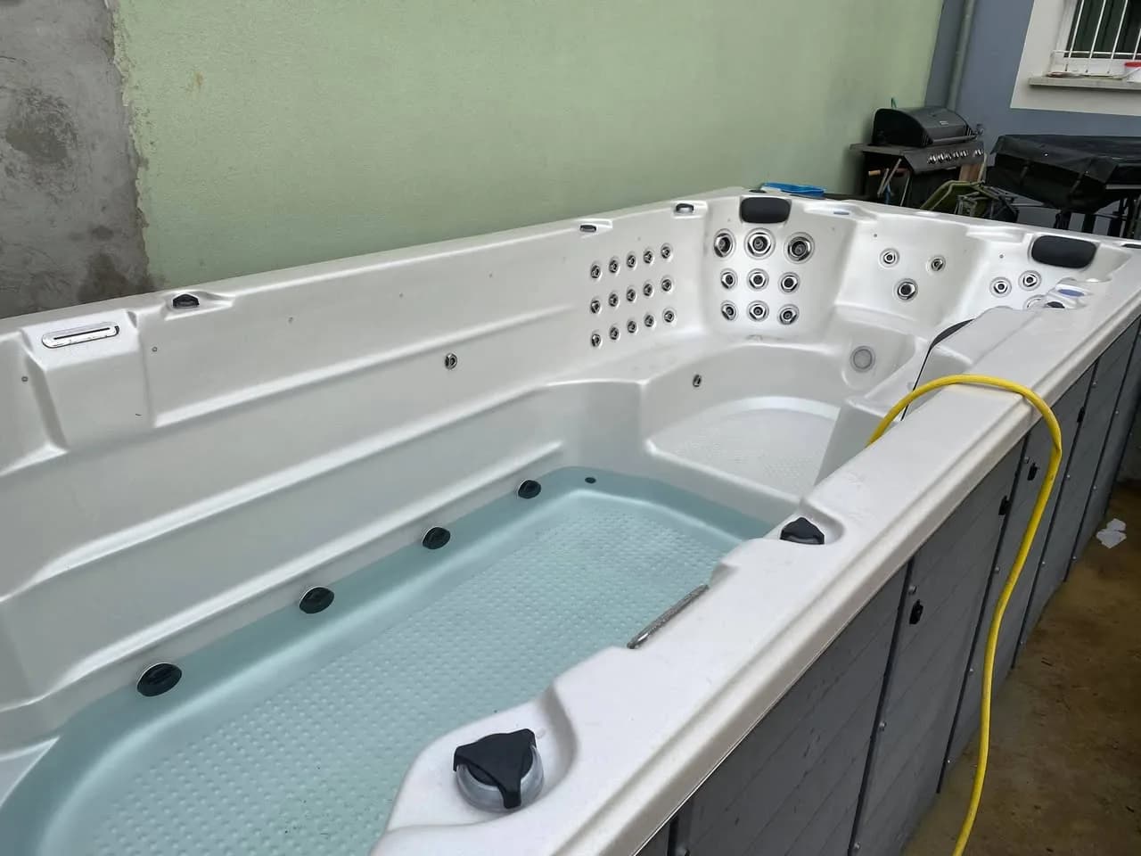 Installation d'un spa de nage Waterloo Full option, cuve blanche et tablier gris foncé
