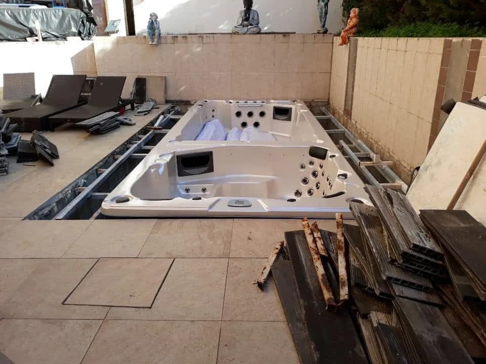 Installation d'un spa de nage Waterloo, sur une terrasse dallée, encadrement en cours