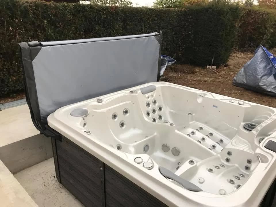 Installation d'un spa Delphina Royal à Colmar, contre une haie, couverture relevée