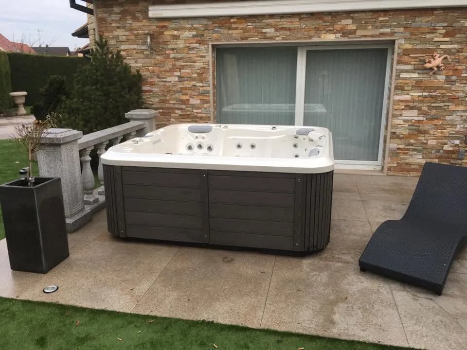 Installation d'un spa Delphina Royal, sur une terrasse dallée, mur en pierre