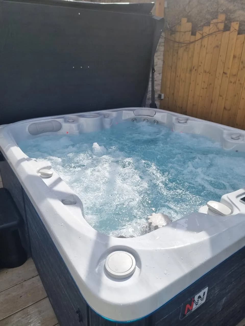 Installation d'un spa Drøbak à Saint-Louis, sur une terrasse devant une palissade en bois