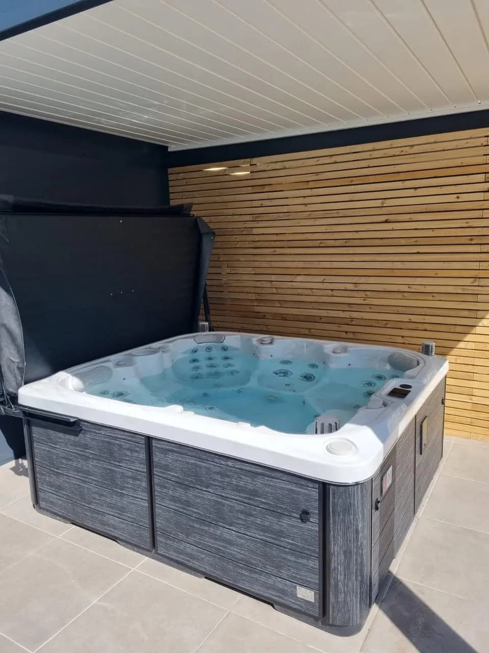 Installation d'un spa Drøbak à Urbès, sous une pergola devant un bardage en bois